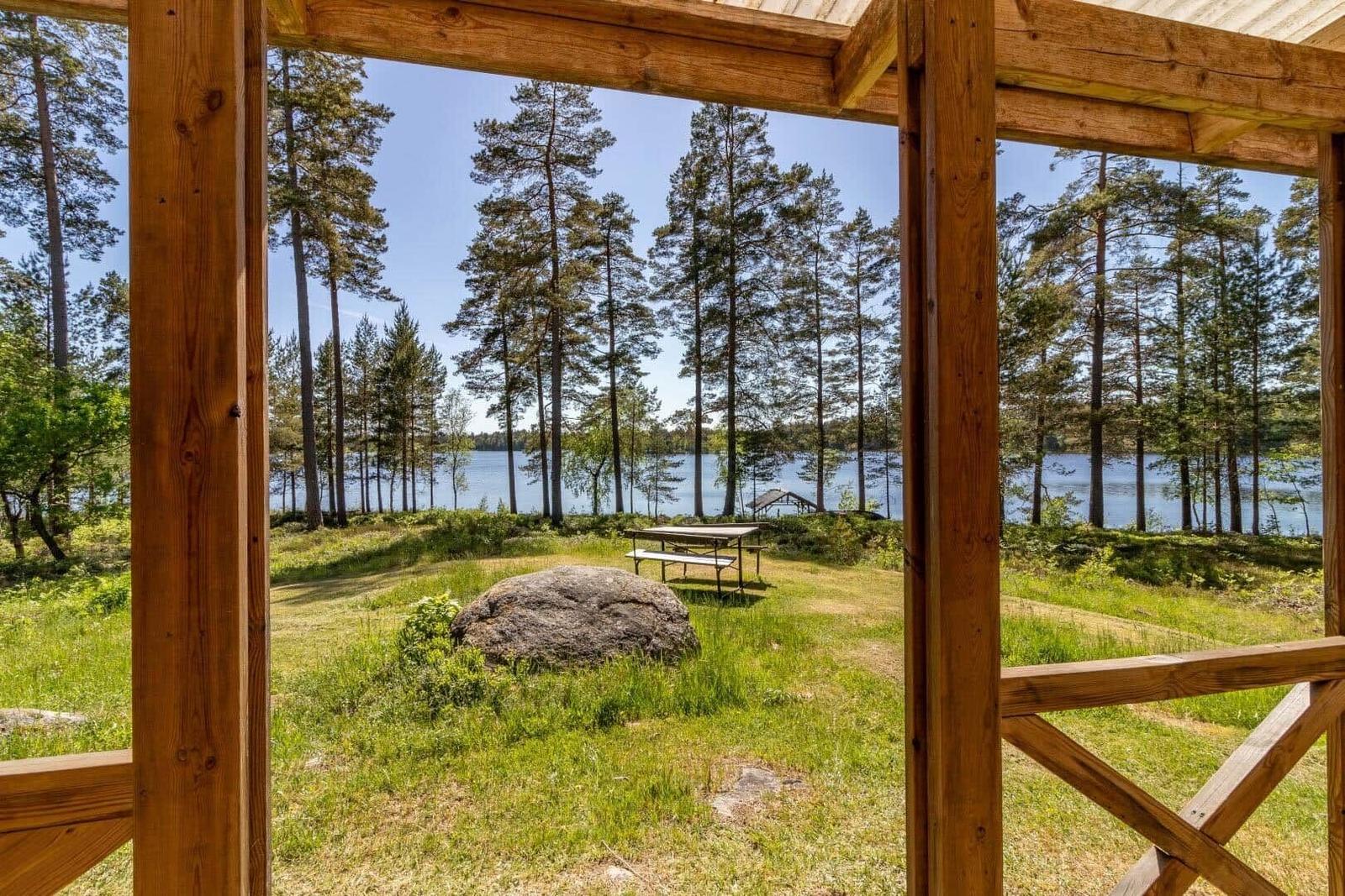 Von der Terrasse aus Blick auf See und Wald mit Picknicktisch und Stein.