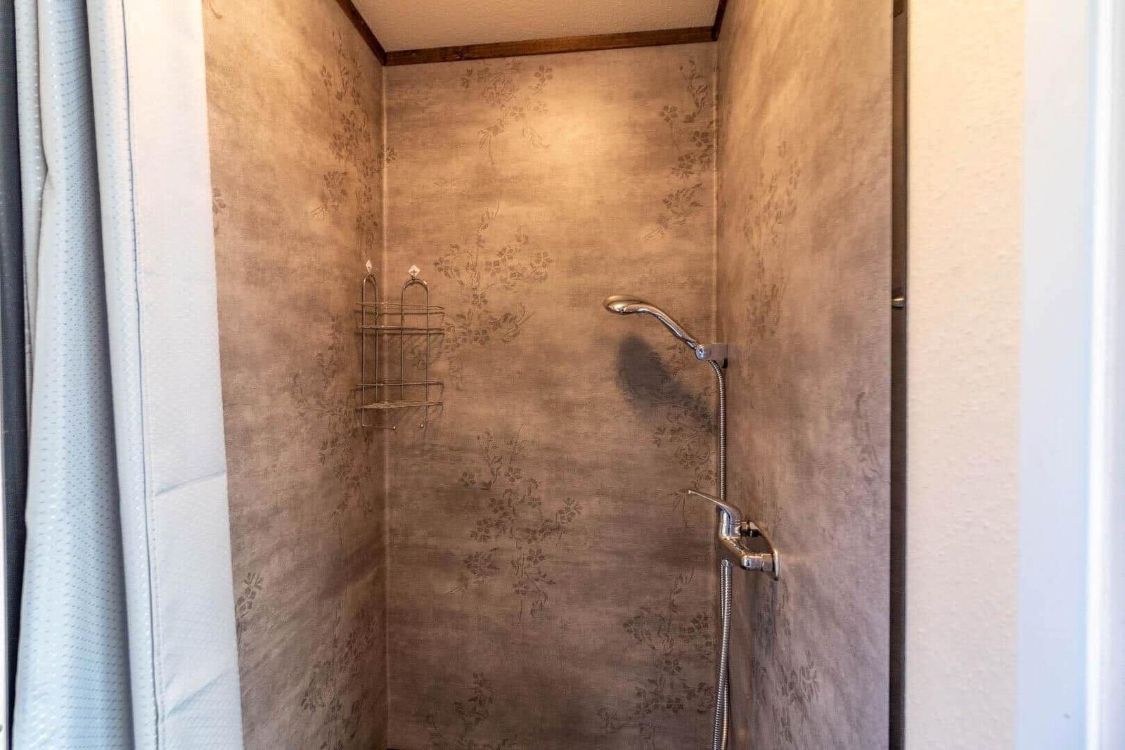 Duschkabine mit floral gemusterter Wand und Duschbrause