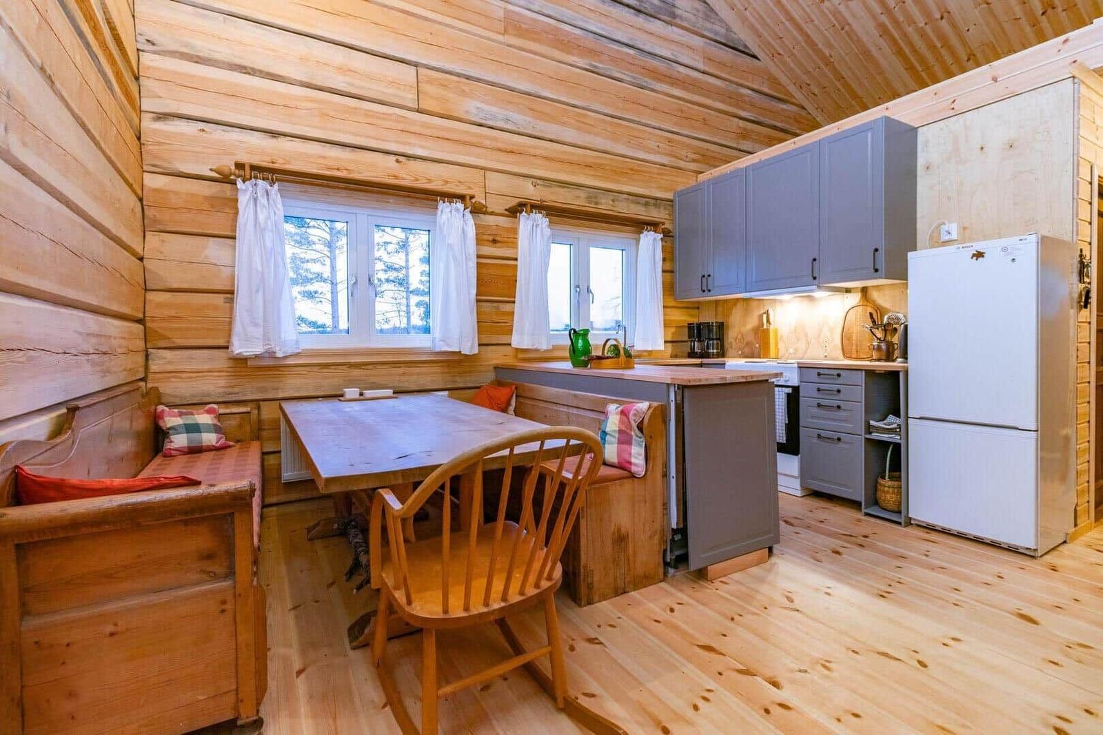 Kitchen with dining area, wooden walls, windows, and cabinets.
