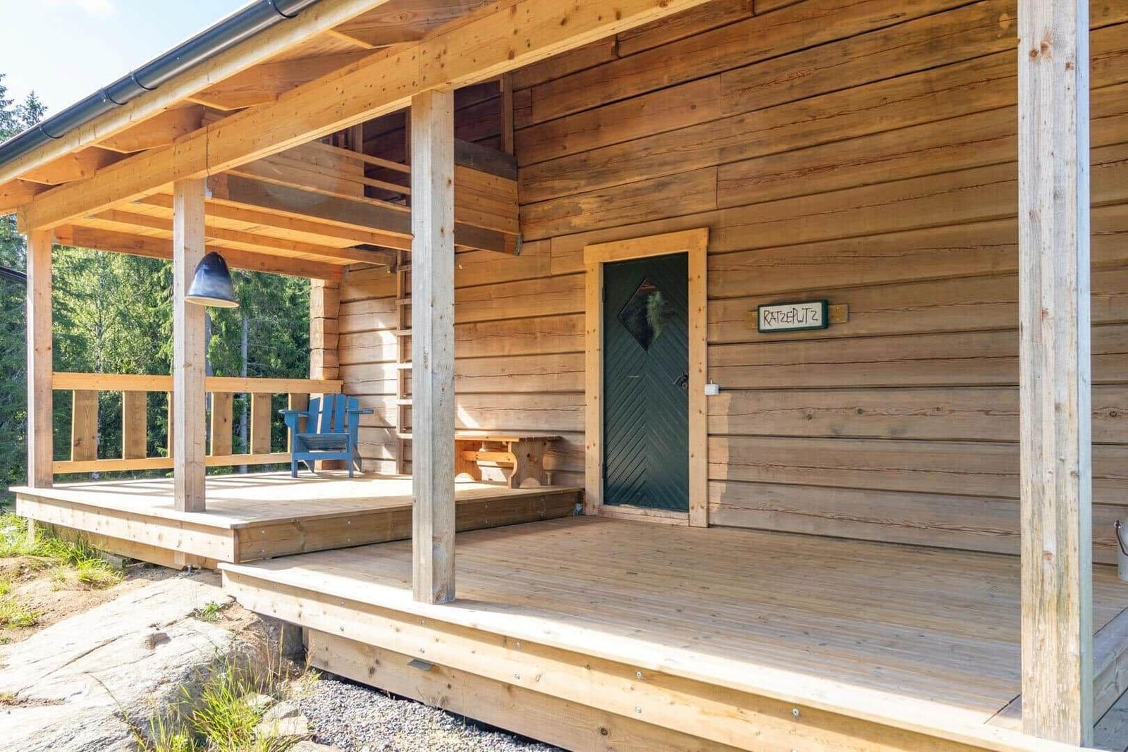 Wooden porch with blue seating and green door.