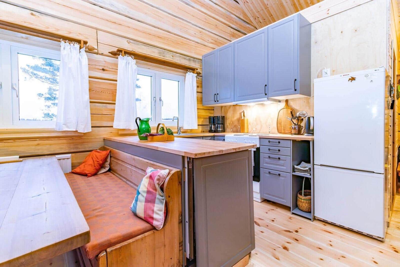 Kitchen with wooden walls, gray cabinets, and seating area with cushions.