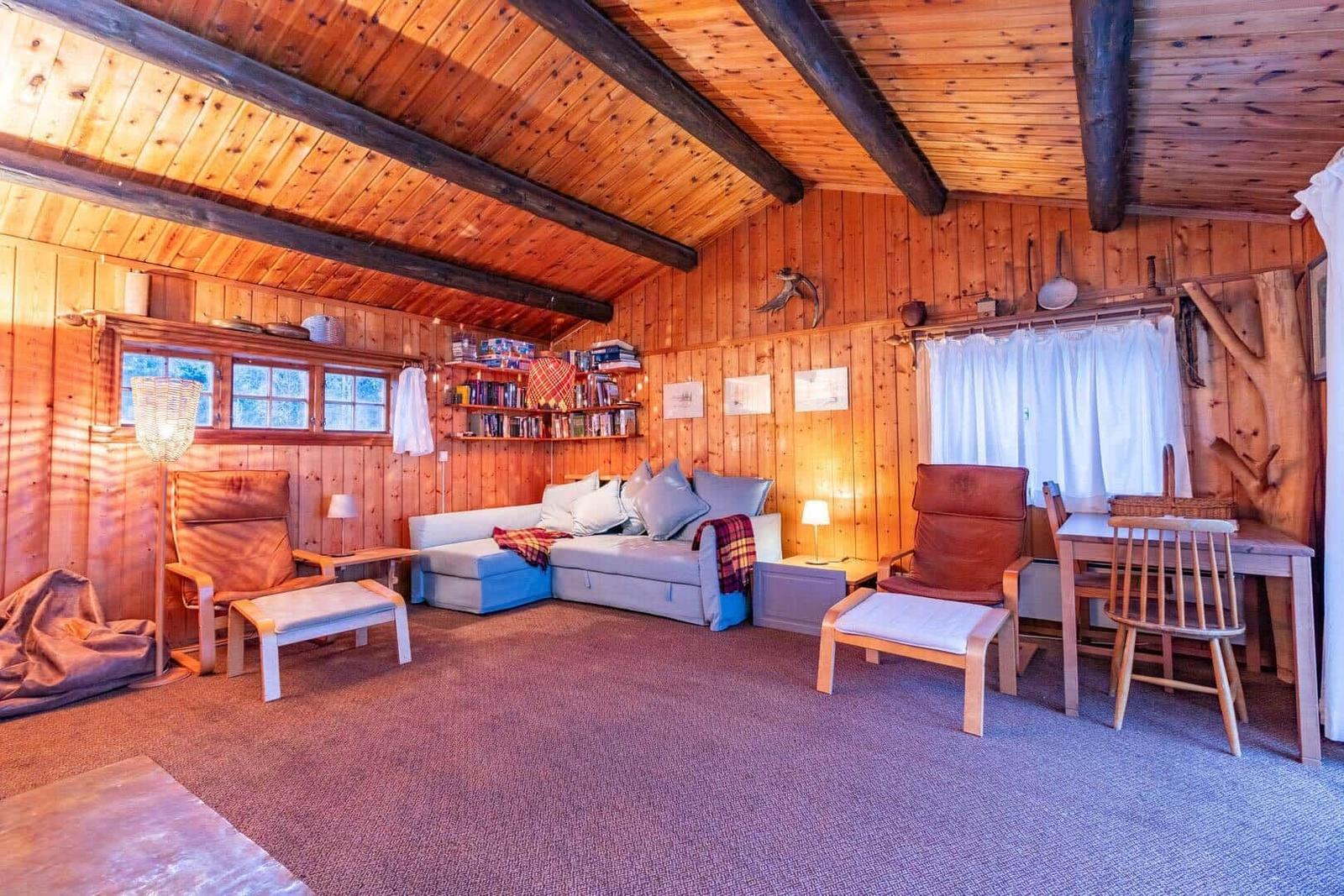 Living room with wooden walls, sofa, two chairs and table