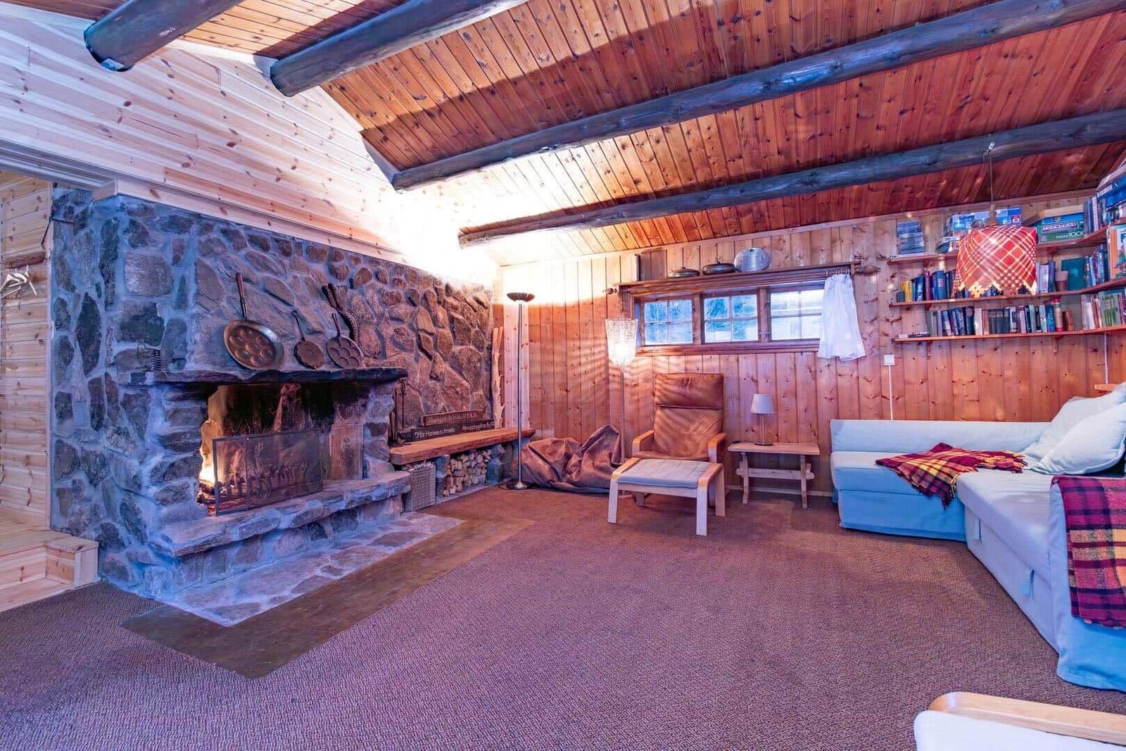 Living room with stone fireplace, wood walls, and sofa.