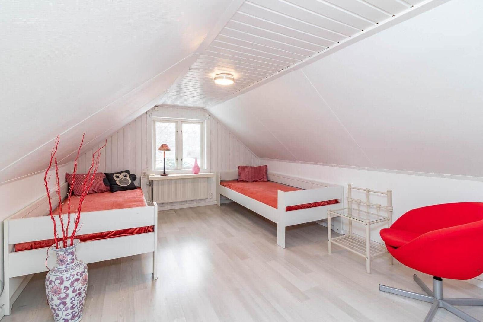 Zimmer mit zwei Betten, rotem Sessel und Fenster