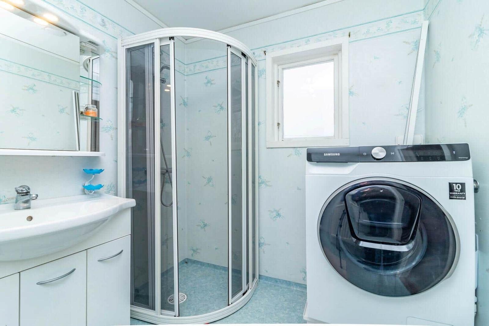 Badezimmer mit Dusche, Waschbecken und Waschmaschine.