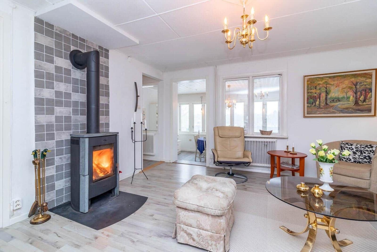 Wohnzimmer mit Kamin, Sitzgelegenheiten und Blick in die Küche.