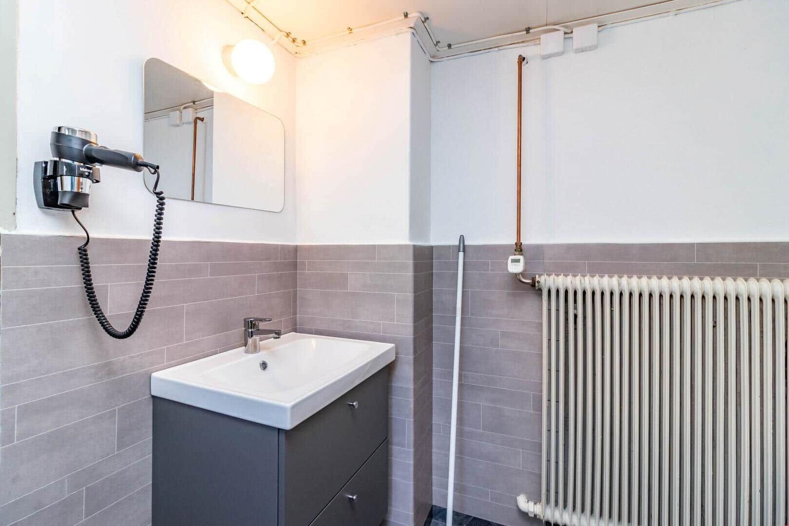 Badezimmer mit Waschbecken, Spiegel und Handtuchhalter.