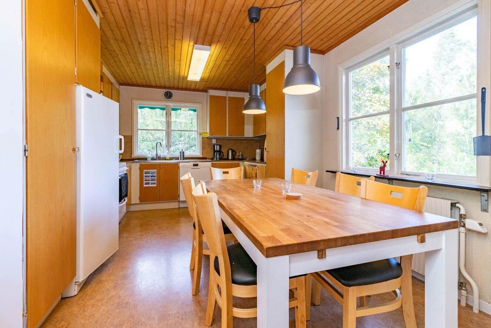 Küche mit Essbereich, Holztisch, Stühle und Fenster zur Natur.