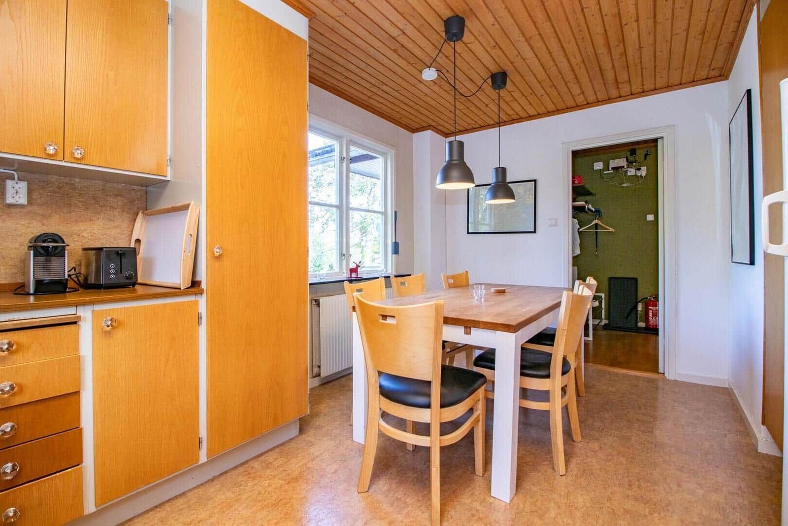 Küche mit Esstisch und Stühlen. Holzdecke und Fenster mit Blick draußen.