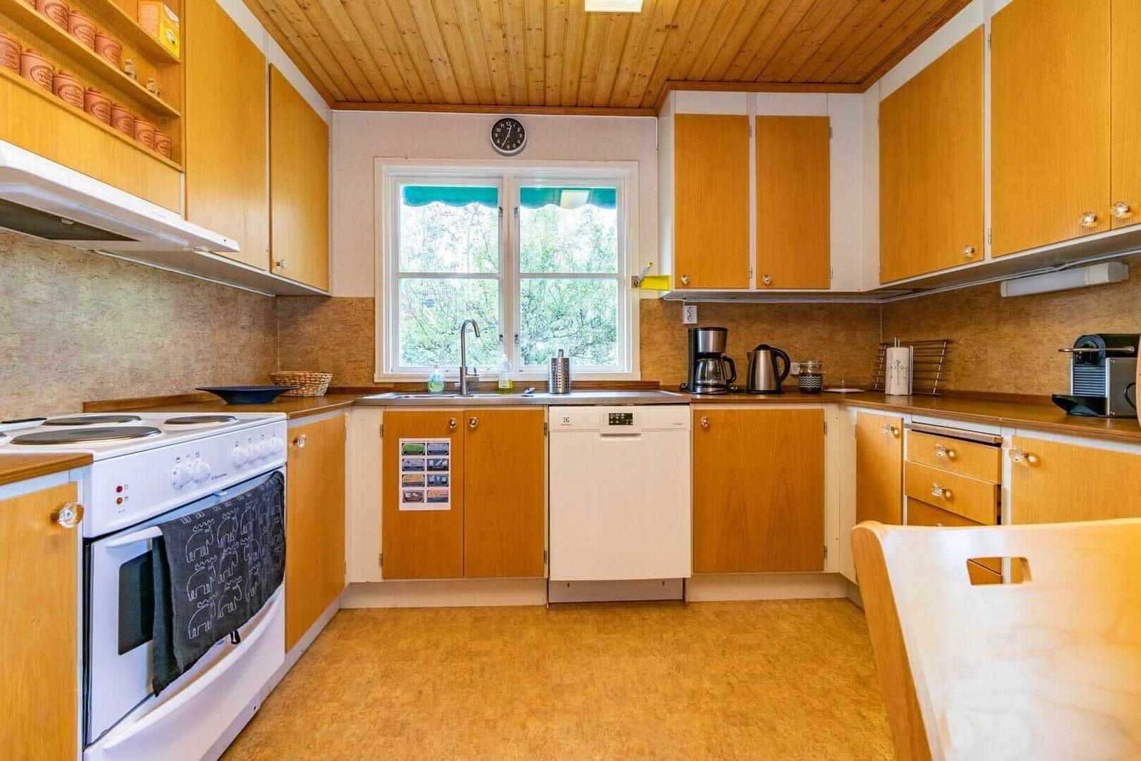 Küche mit Holzmöbeln, Spüle, Waschmaschine und Fenster.