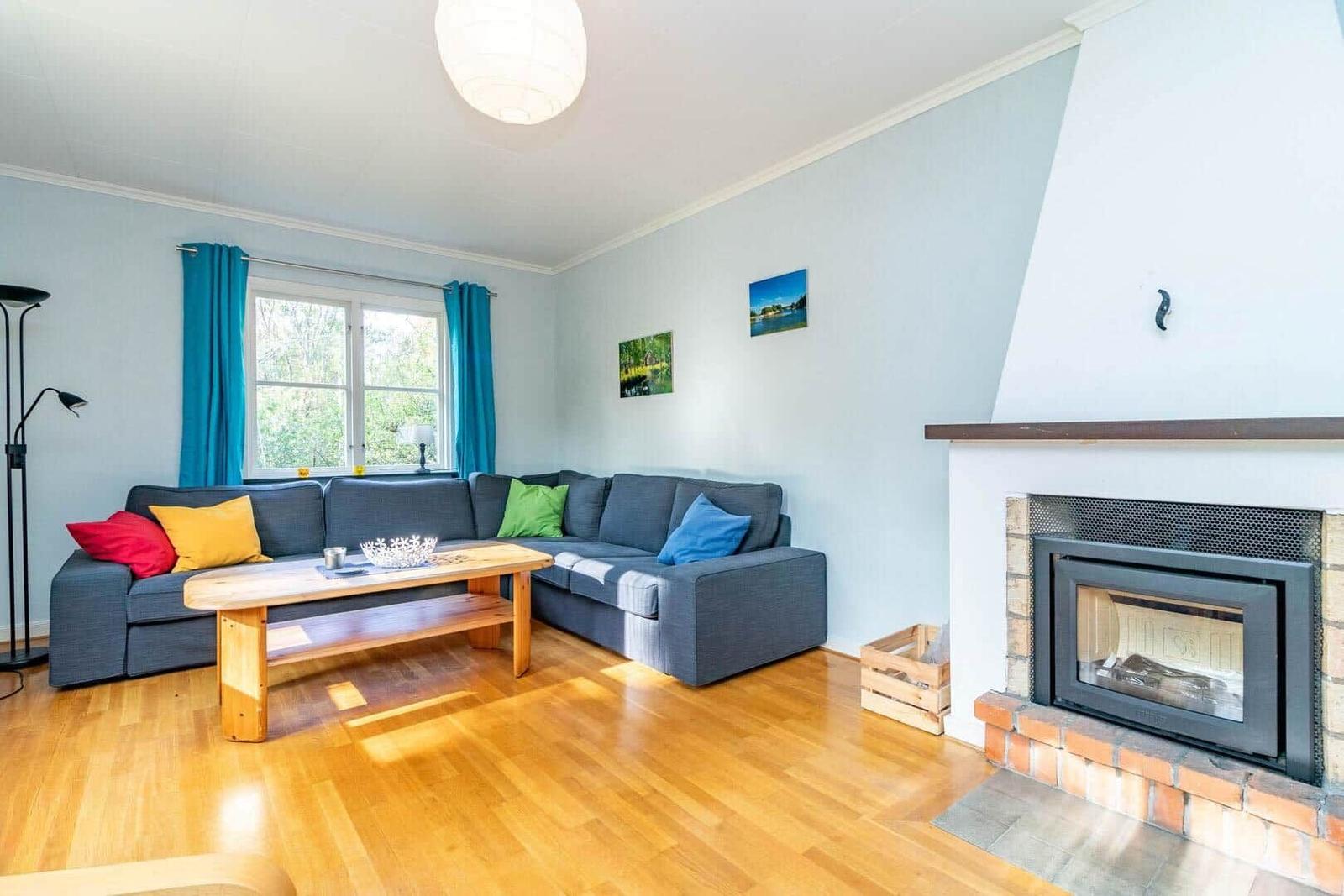 Wohnzimmer mit Sofa, Kamin und Holzboden.
