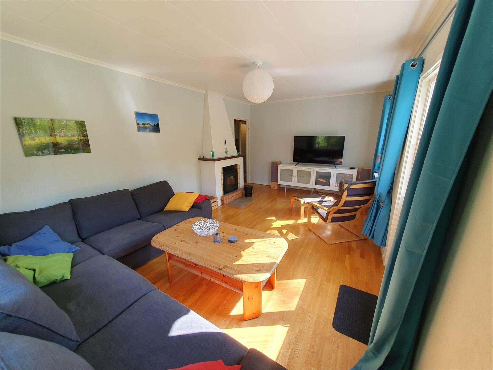 Wohnzimmer mit Sofa, Kamin, Fernseher und Holzboden.