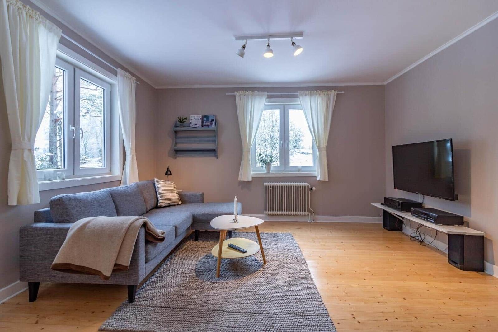 Wohnzimmer mit Sofa, Couchtisch und Fernseher an der Wand.