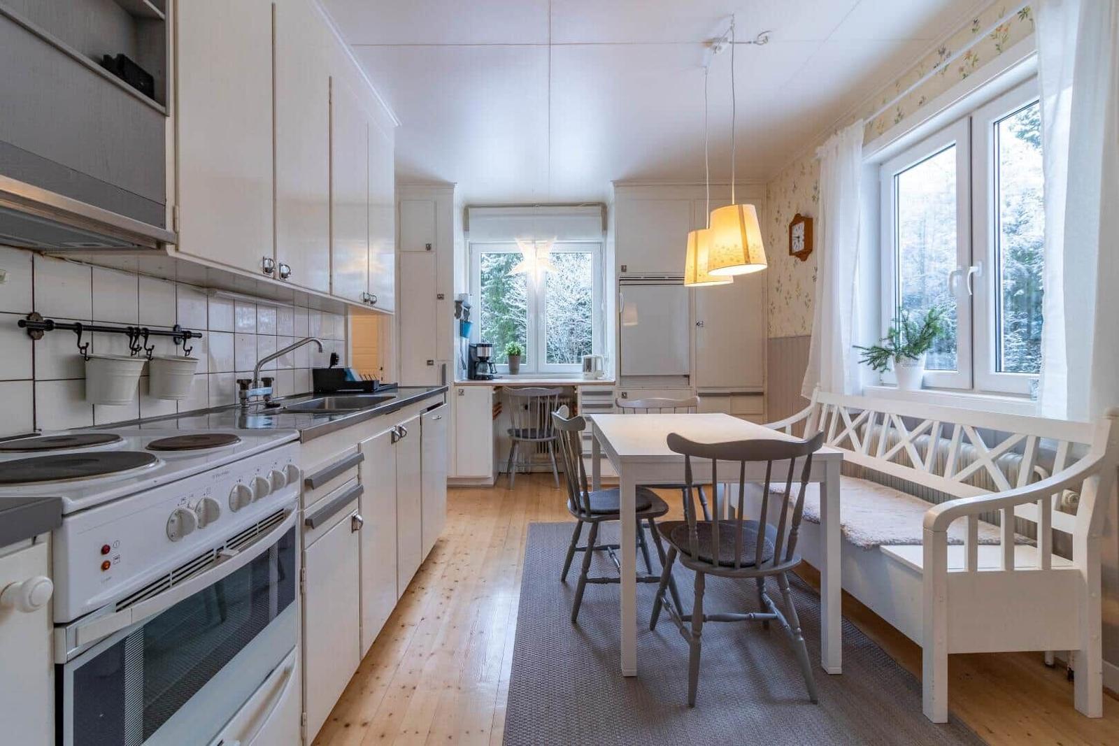 Küche mit Esstisch, Fenster und weißen Möbeln.