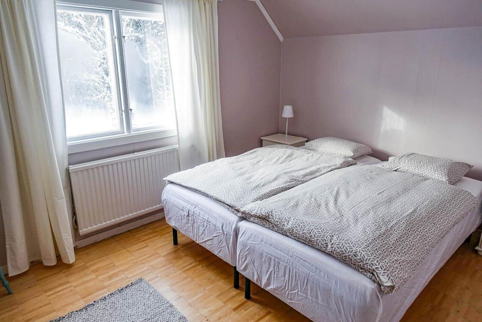 Schlafzimmer mit Doppelbett, Fenster und Holzboden.