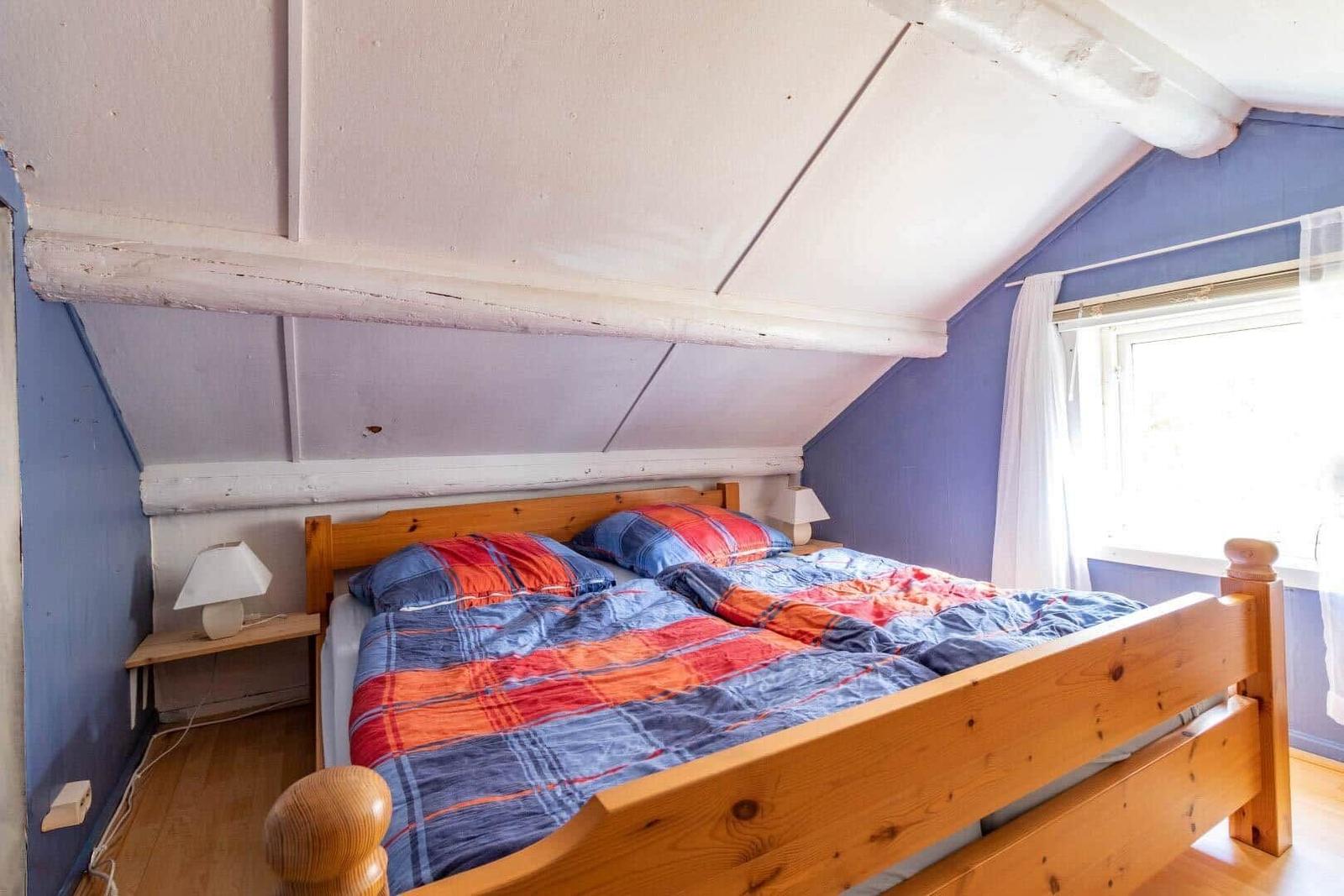 Bedroom with wooden bed, blue walls, and sloped ceiling.