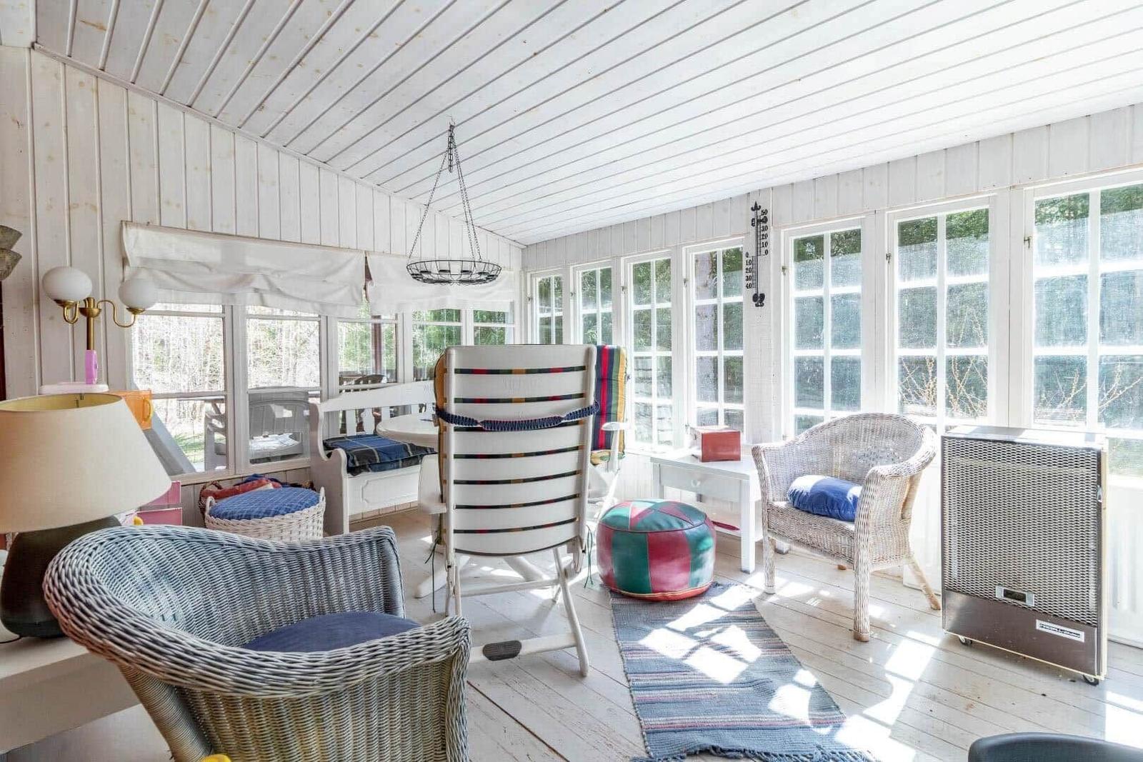 A room with white walls and windows, furniture, and a rug.