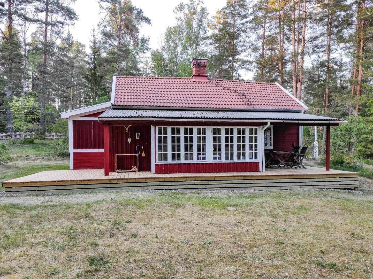 Red wooden house with terrace and garden surrounded by trees
