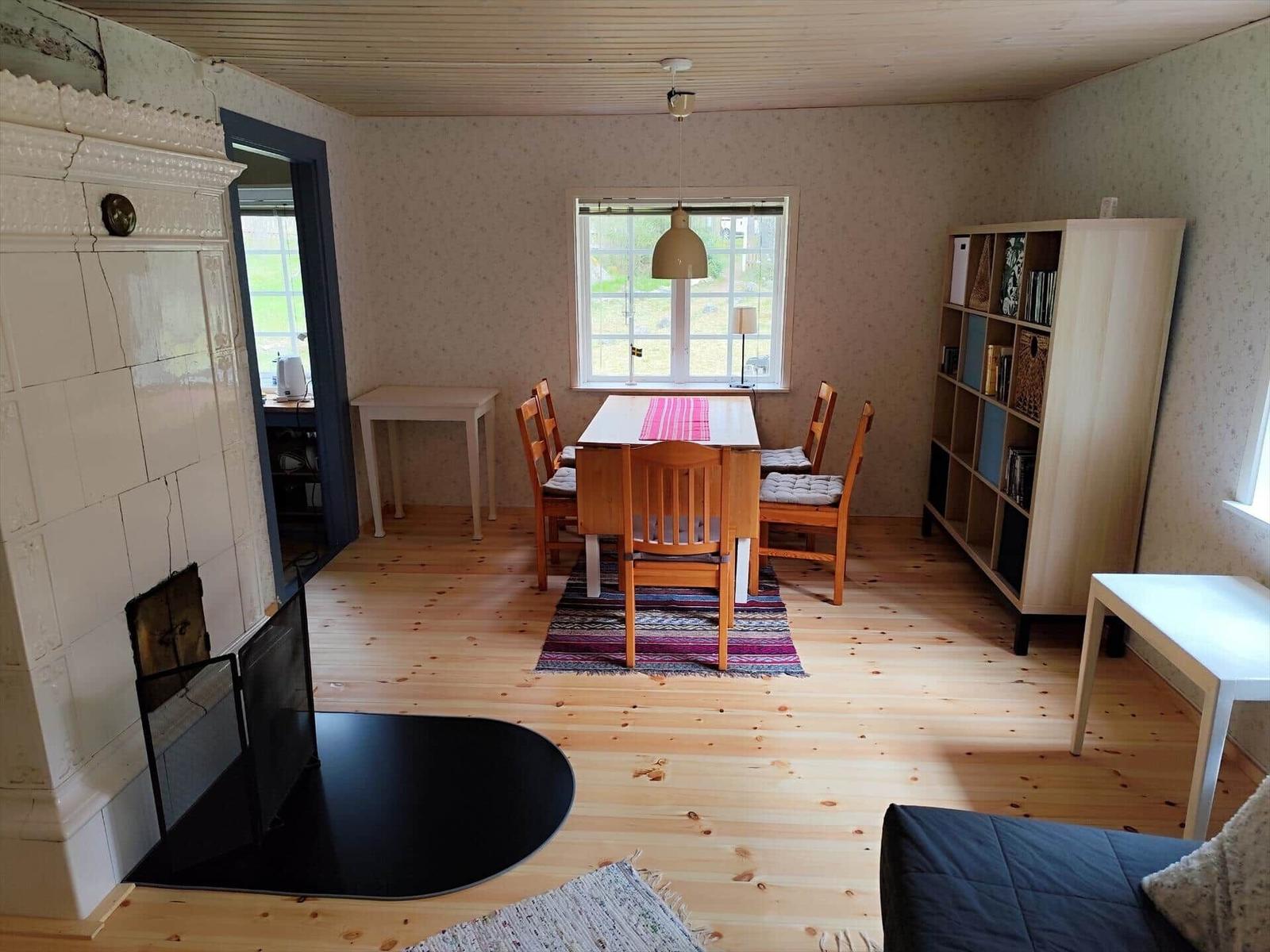 Dining room with wooden floor, table, chairs, and bookshelf.