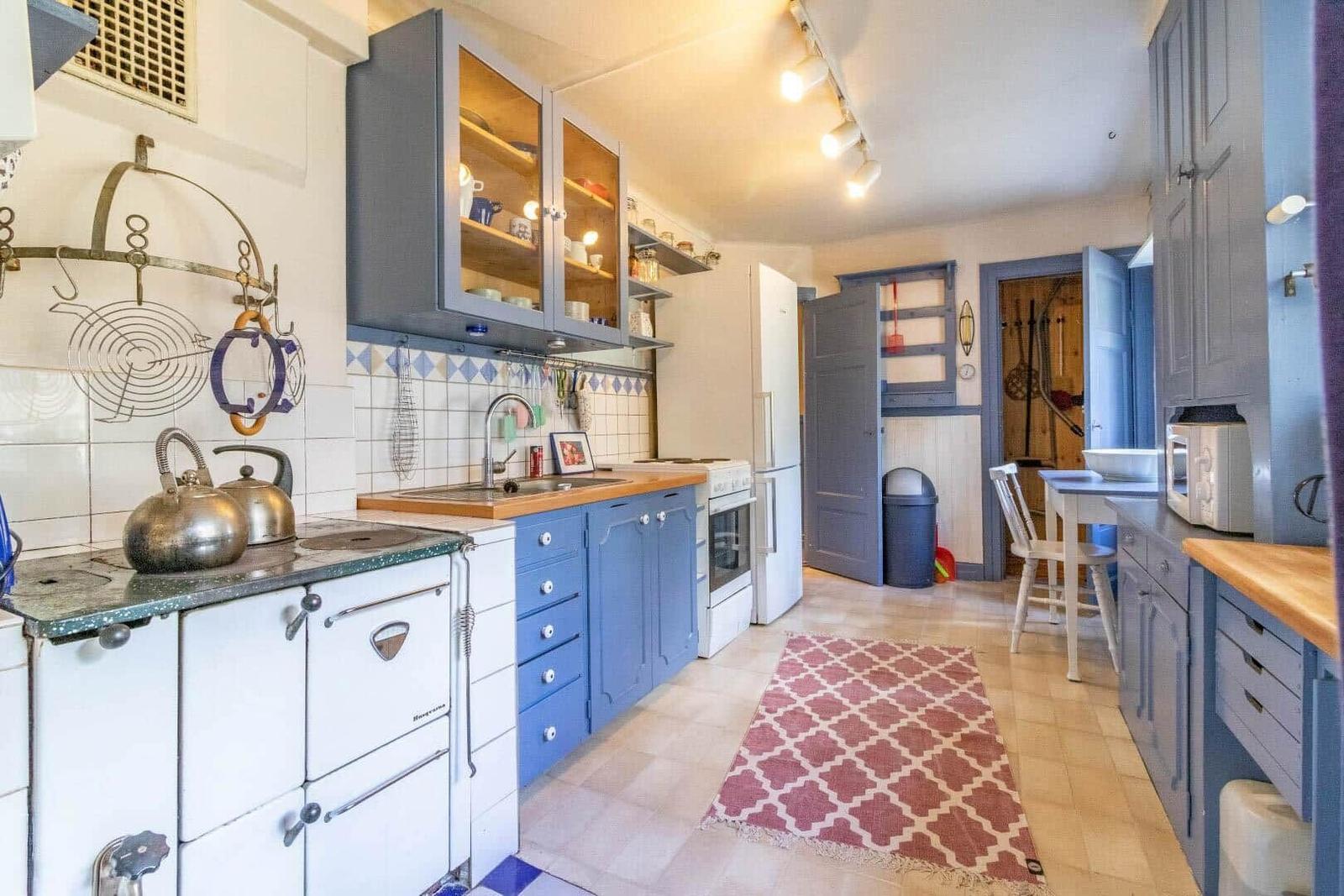 Kitchen with blue cabinets, wooden countertops, and red rug