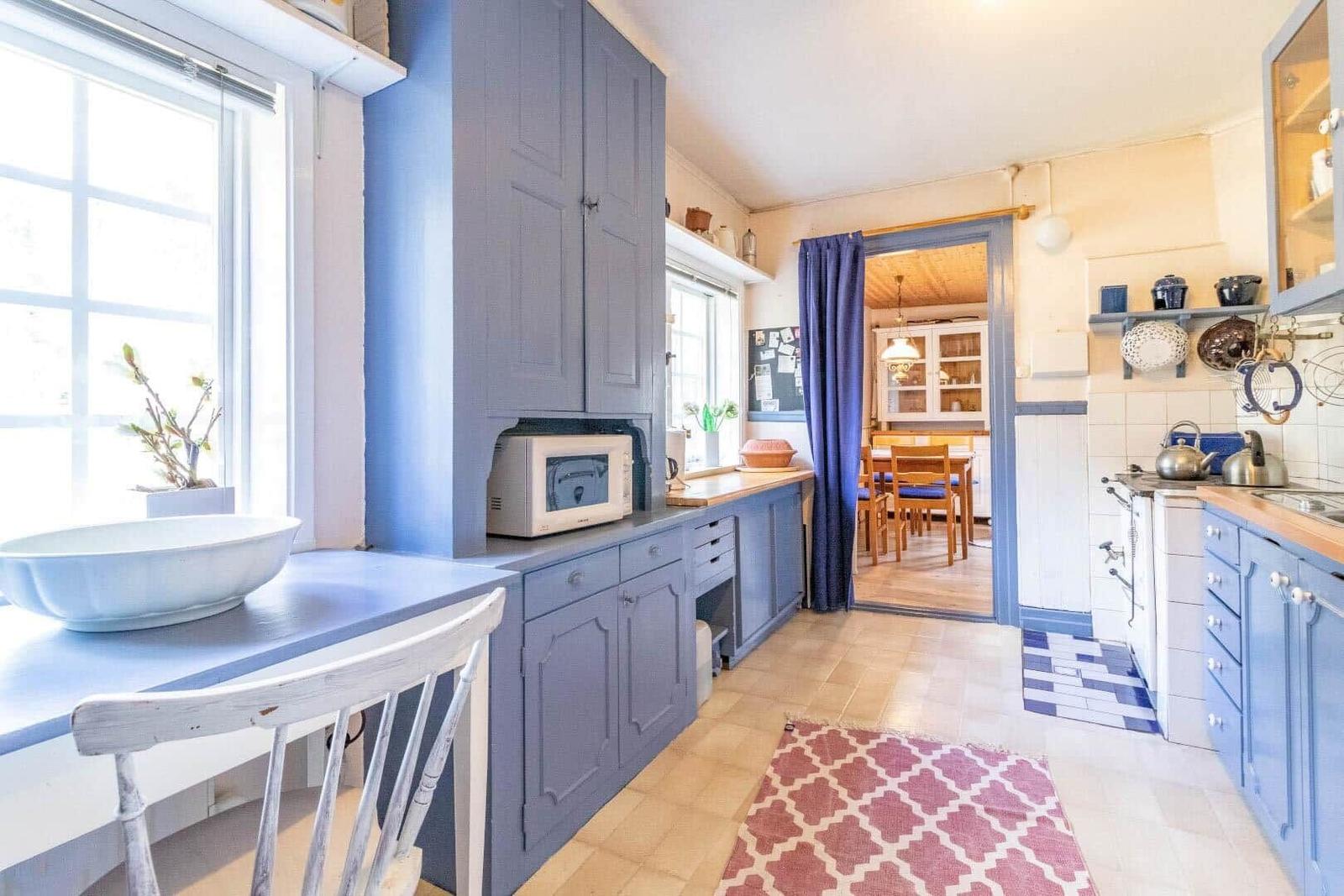 Kitchen with blue cabinets, wooden surfaces, and view into dining room.