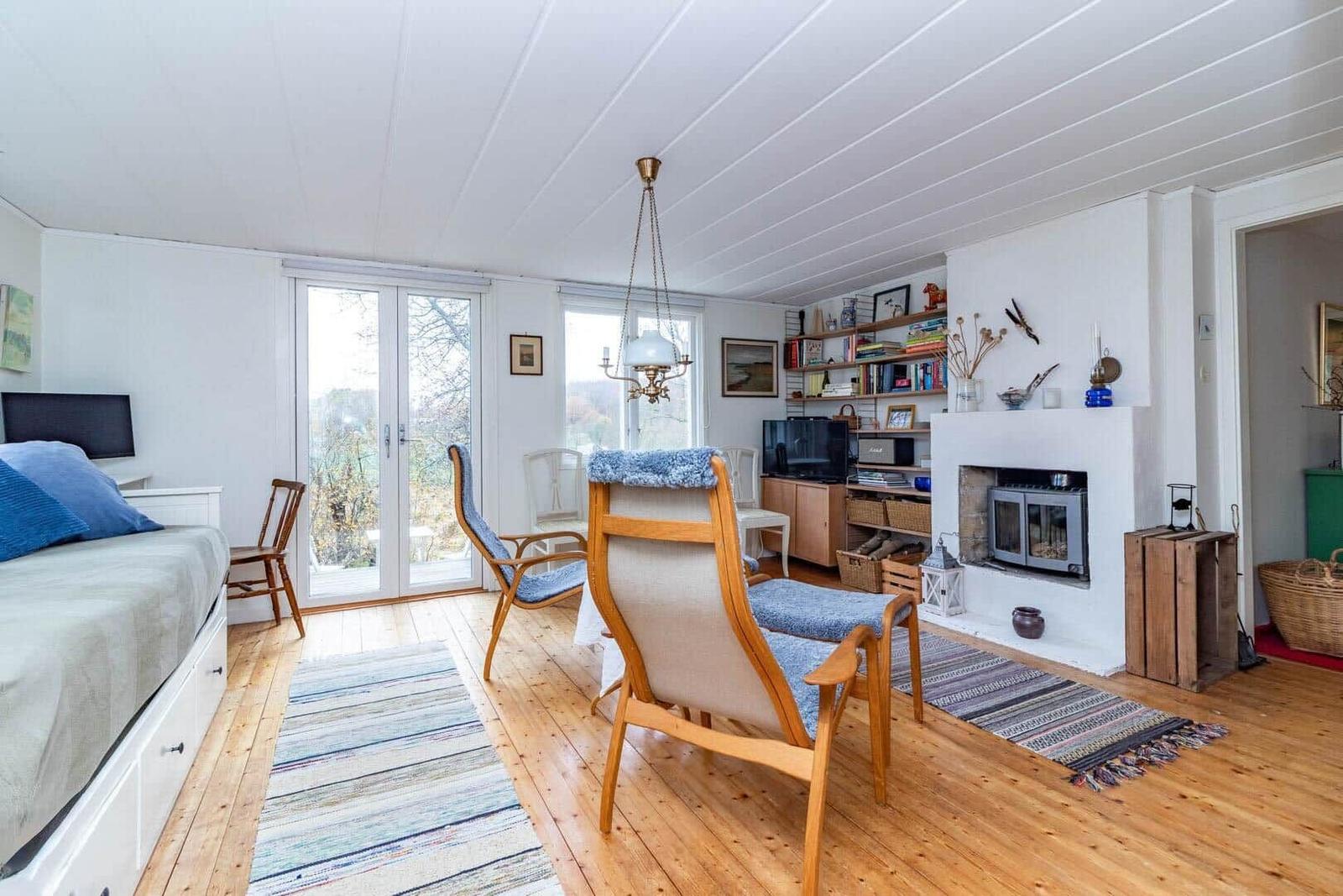 Wohnraum mit Bett, Sitzgelegenheiten und Kamin. Holzboden und große Fenster.