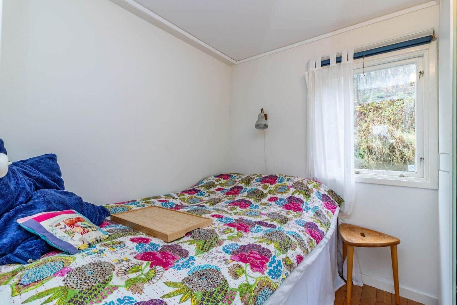 Schlafzimmer mit Bett, Fenster und Holzstuhl.