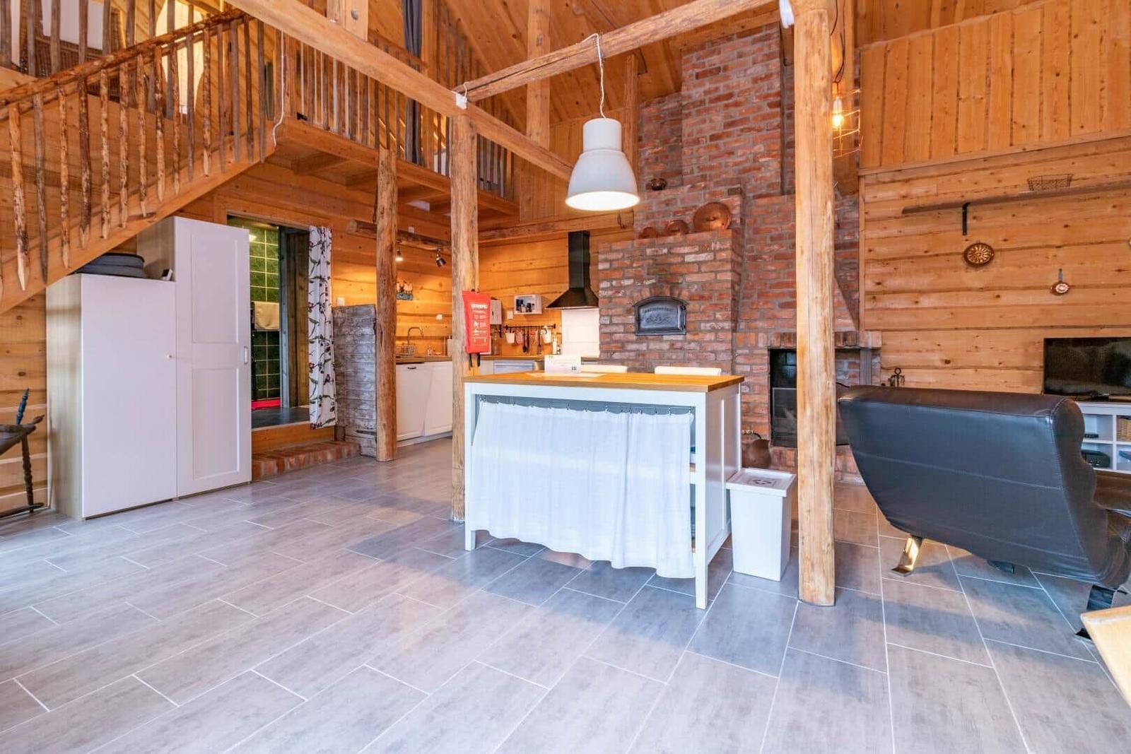 Großes Wohnzimmer mit Holzdecke, Kamin und Kücheninsel.