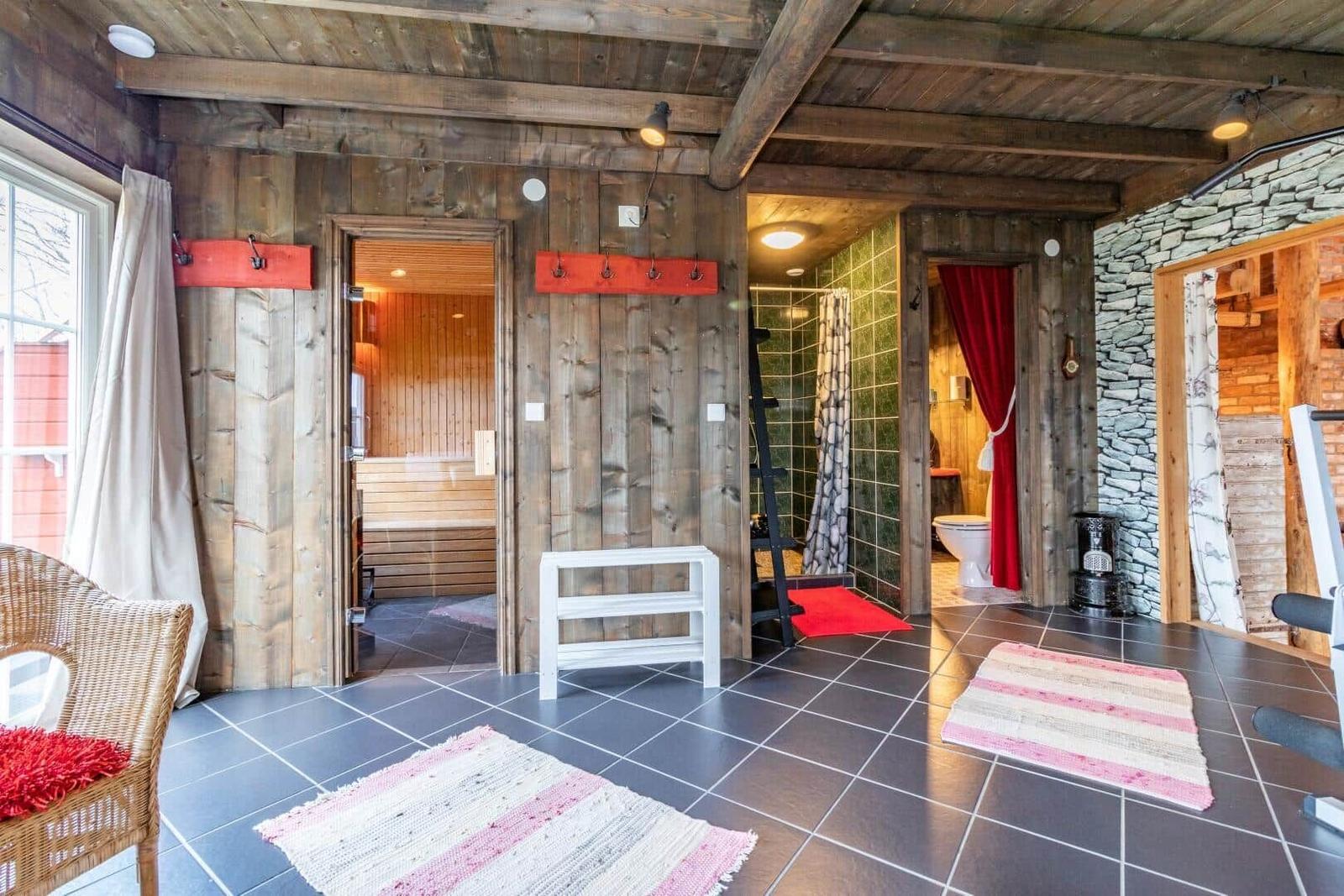 Raum mit Sauna, Dusche und Toilette, Holzwände und Steinwand, Teppiche und Stühle