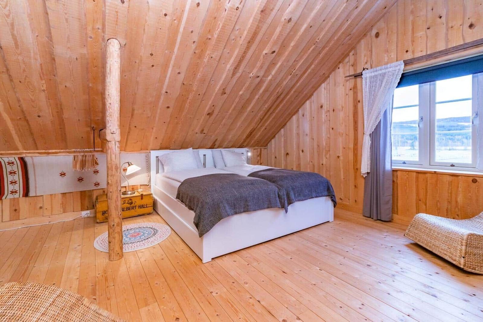 Schlafzimmer mit Holzwand, Bett und Fenster mit Blick.