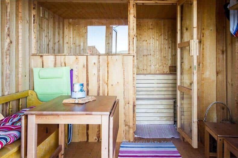 Holzsauna mit Sitzbank, Tisch und grüner Stuhlecke