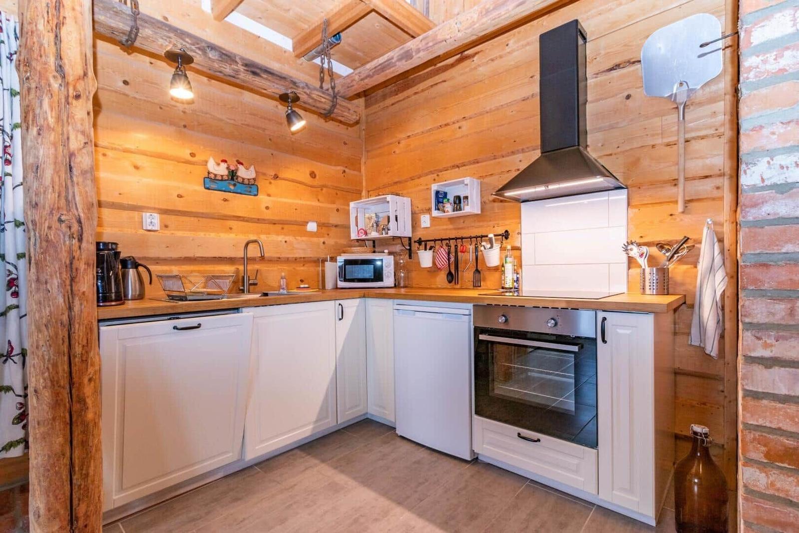 Küche mit Holzwänden, weißen Schränken und Edelstahlherd.