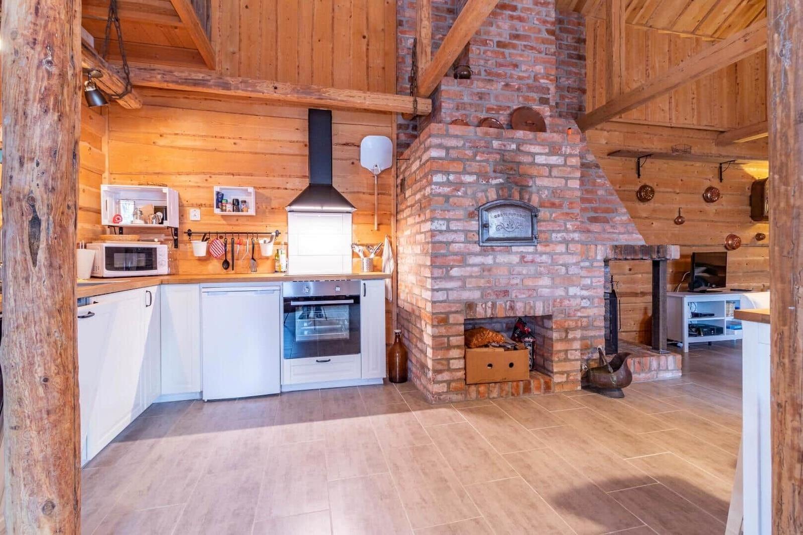Küche mit Backofen und Backofen, großer Kamin und Holzdecke.