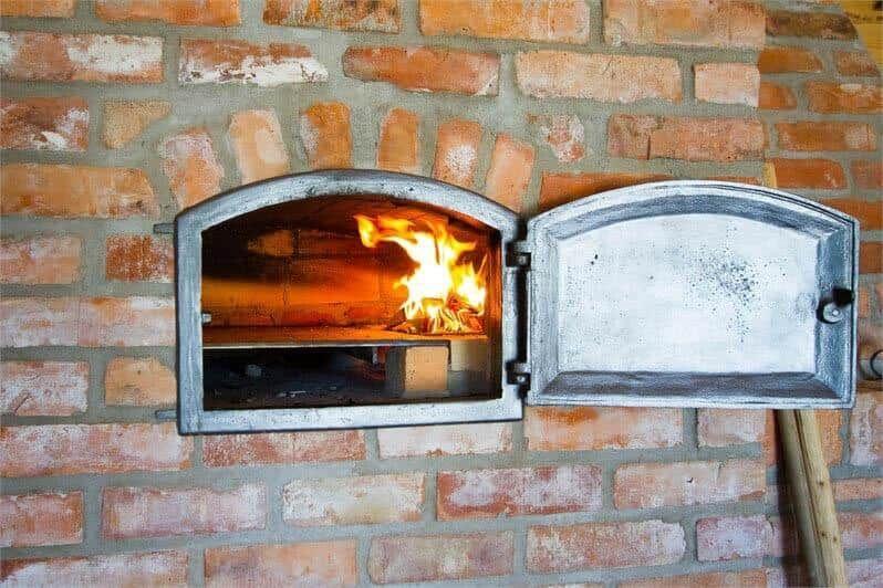 Ein Ofen mit brennendem Feuer in einer Backsteinwand.