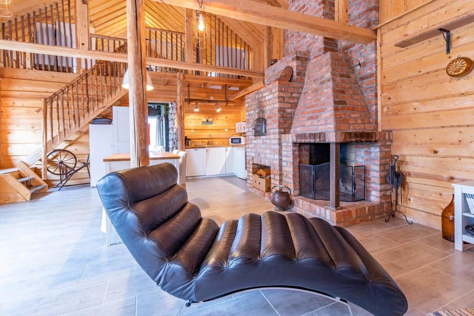 Großer Raum mit Holzverkleidung, Kamin und braunem Ledersofa.