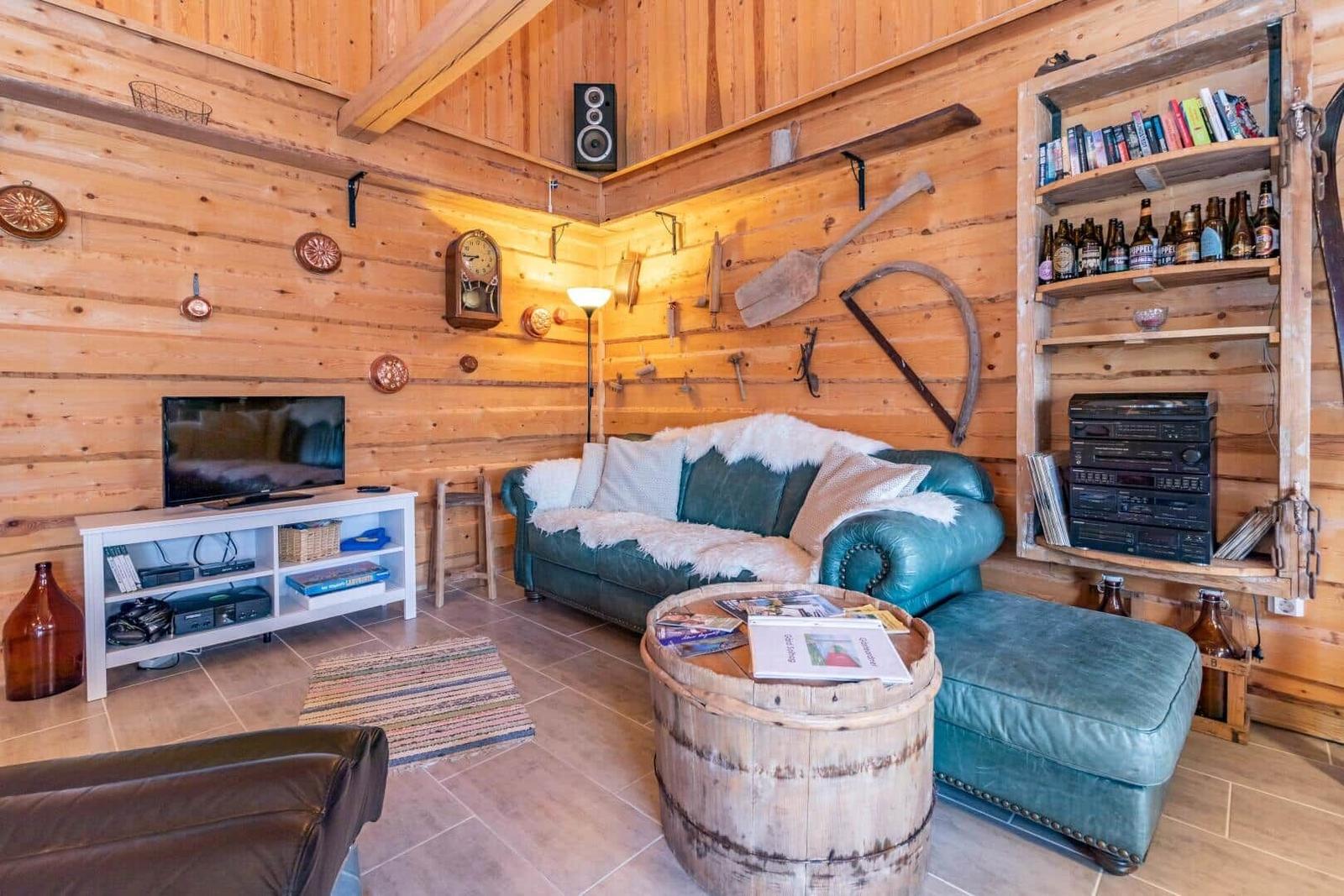 Wohnzimmer mit Holzwand, Sofa, Fernseher und Kamin.