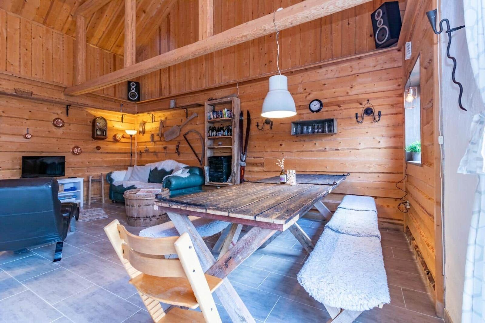 Großer Holzraum mit Esstisch, Sofa und Fernseher an der Wand.