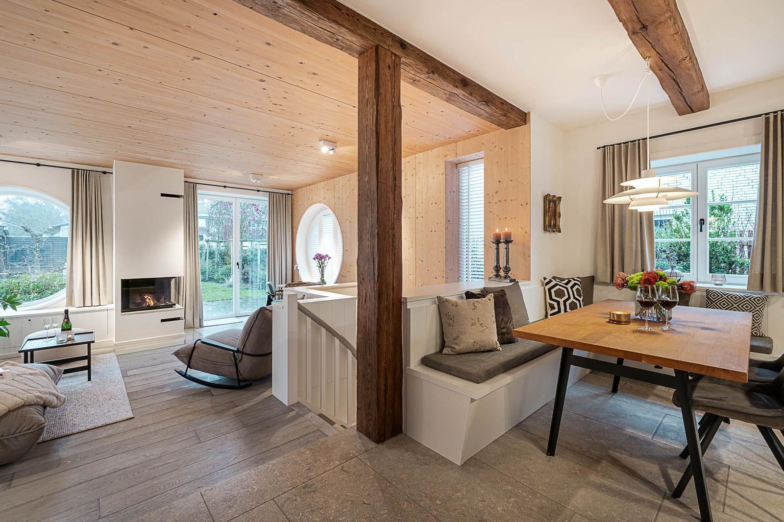 Wohn- und Essbereich mit Holzdecke, Sitzbank, Esstisch und Kamin.
