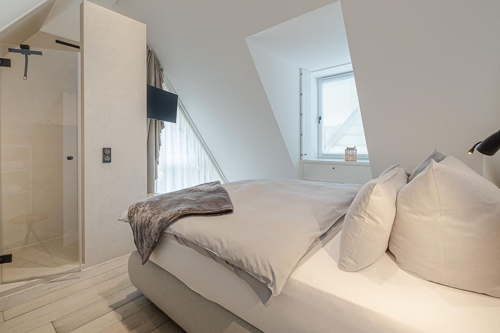 Schlafzimmer mit Dachschrägen, Bett, TV und Dusche