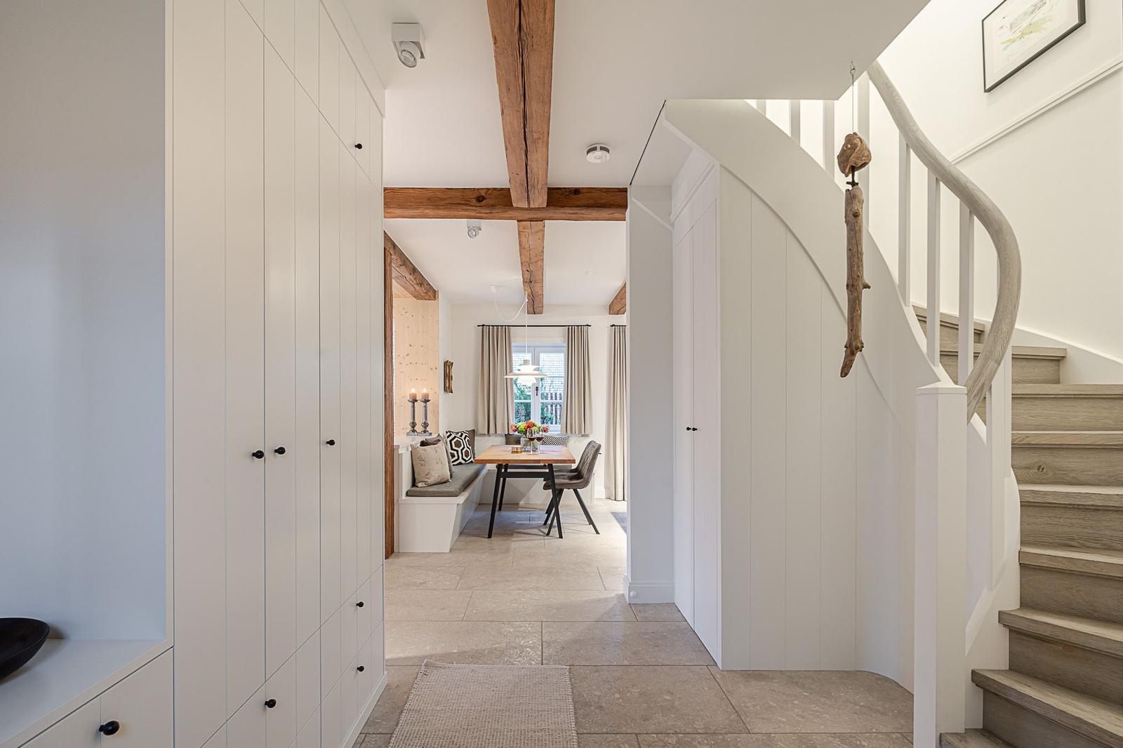 Eingangsbereich mit Treppe und Blick in Essbereich mit Tisch und Sitzbank.