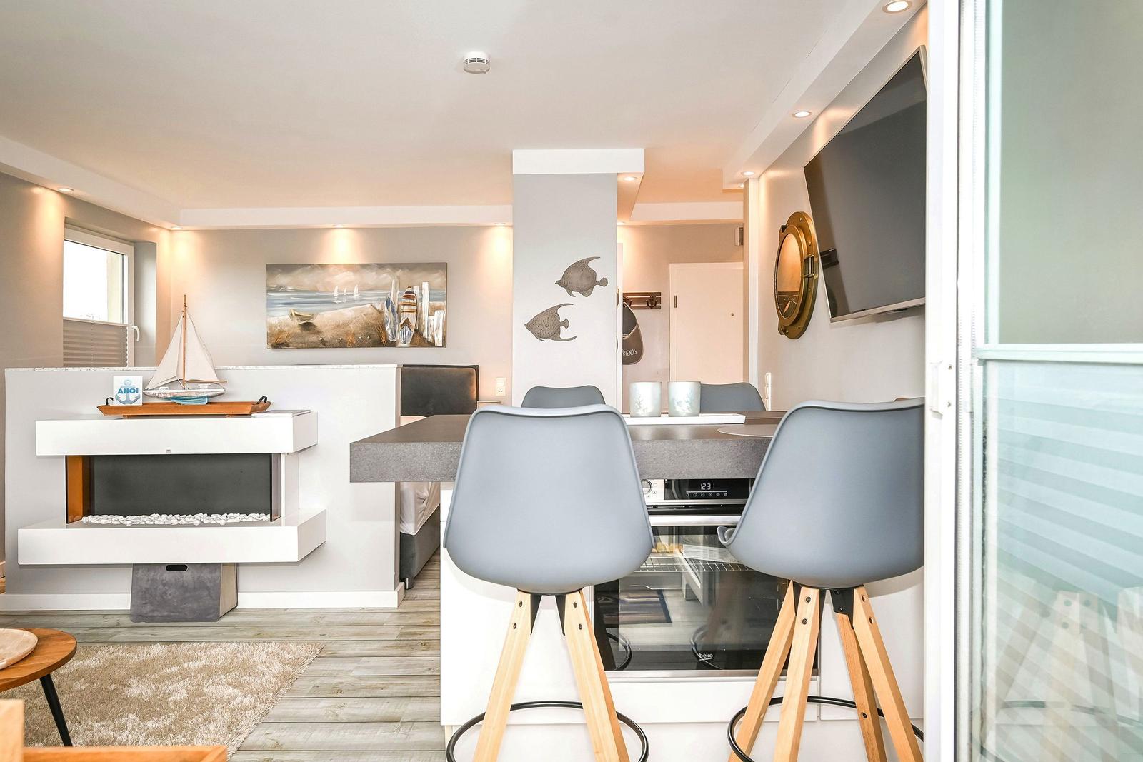 Küche mit Sitzgelegenheit, Fernseher und Wanddekoration. Flur und Wohnbereich sichtbar.