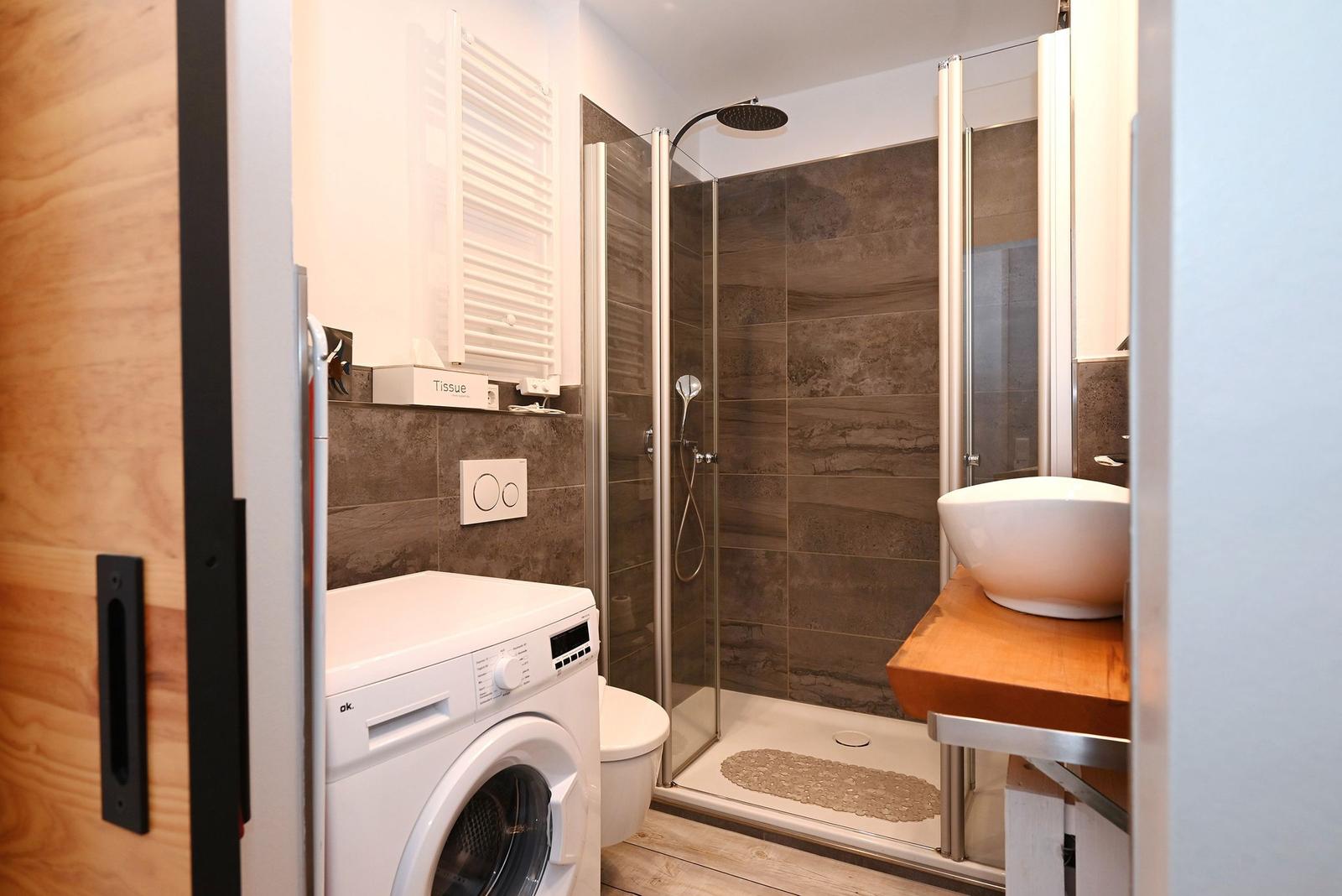 Bad mit Dusche, Waschmaschine und Waschtisch mit Keramikschale.