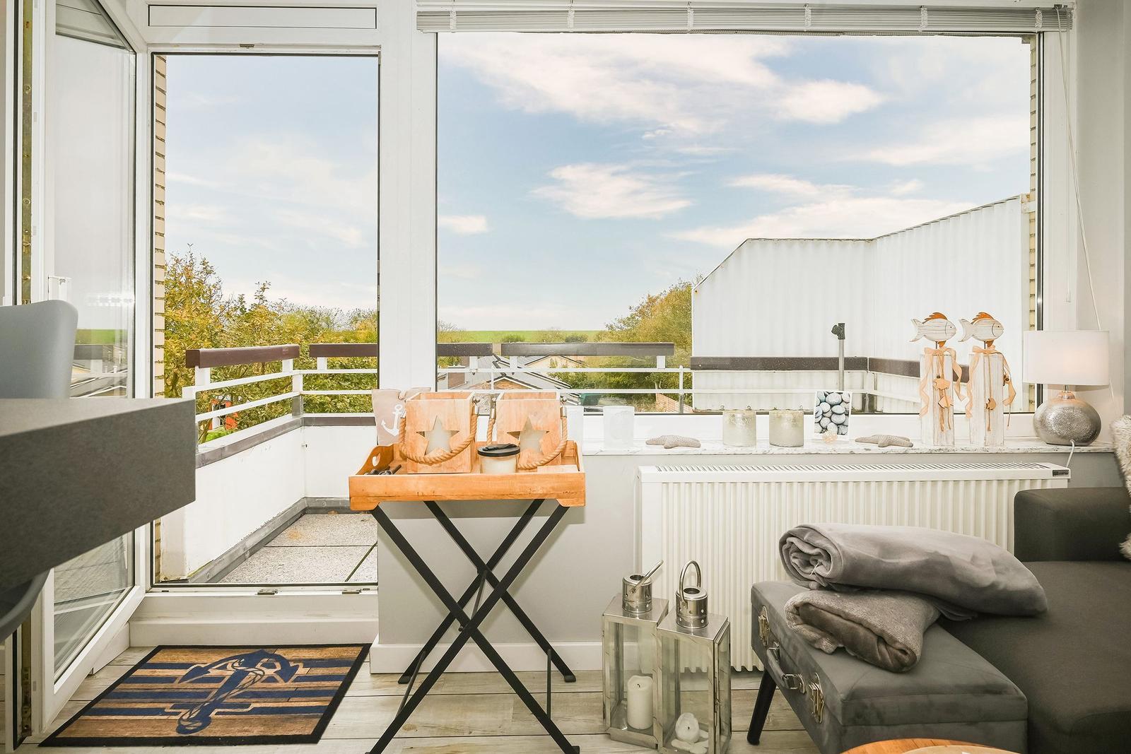 Balkon mit Sicht auf Grünflächen und Himmel. Möbel und Dekoration sind sichtbar.
