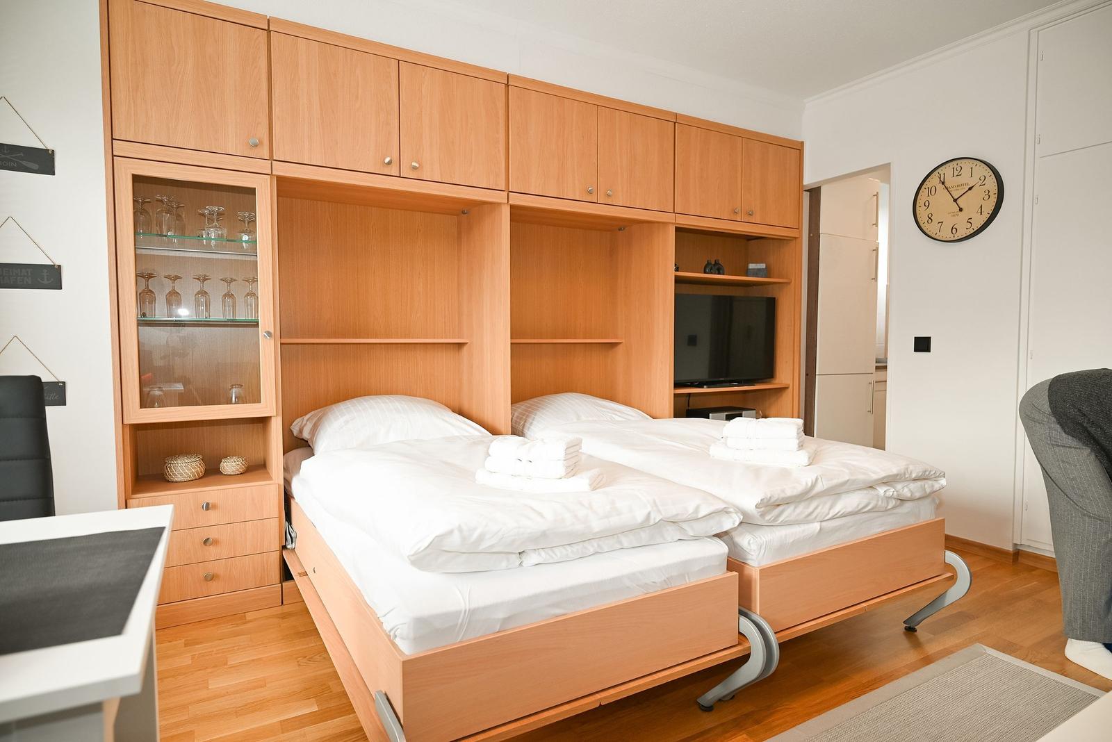 Zwei Betten unter Holzmöbeln mit Schrank und Fernseher.