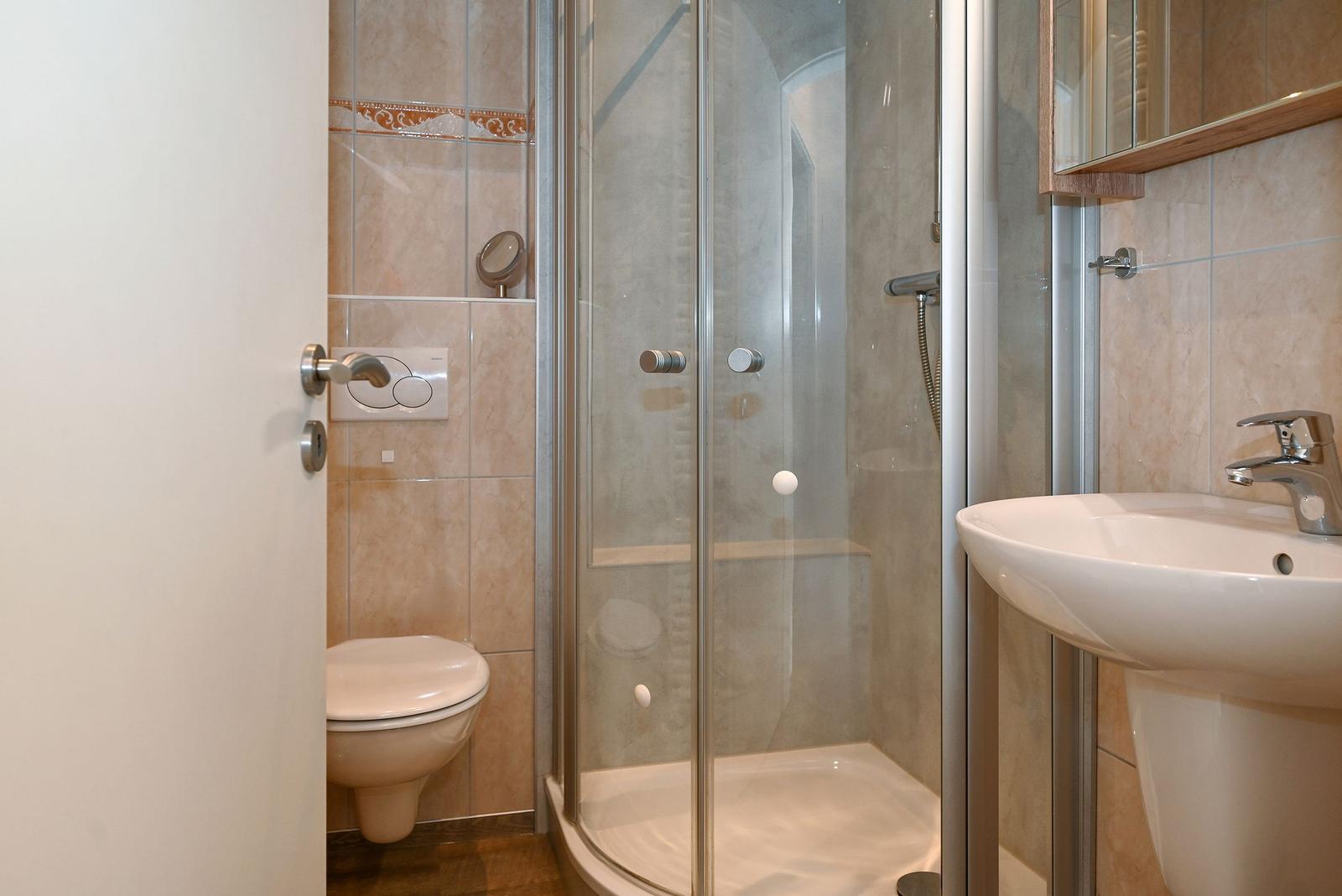 Badezimmer mit Dusche, Waschbecken und Toilette.