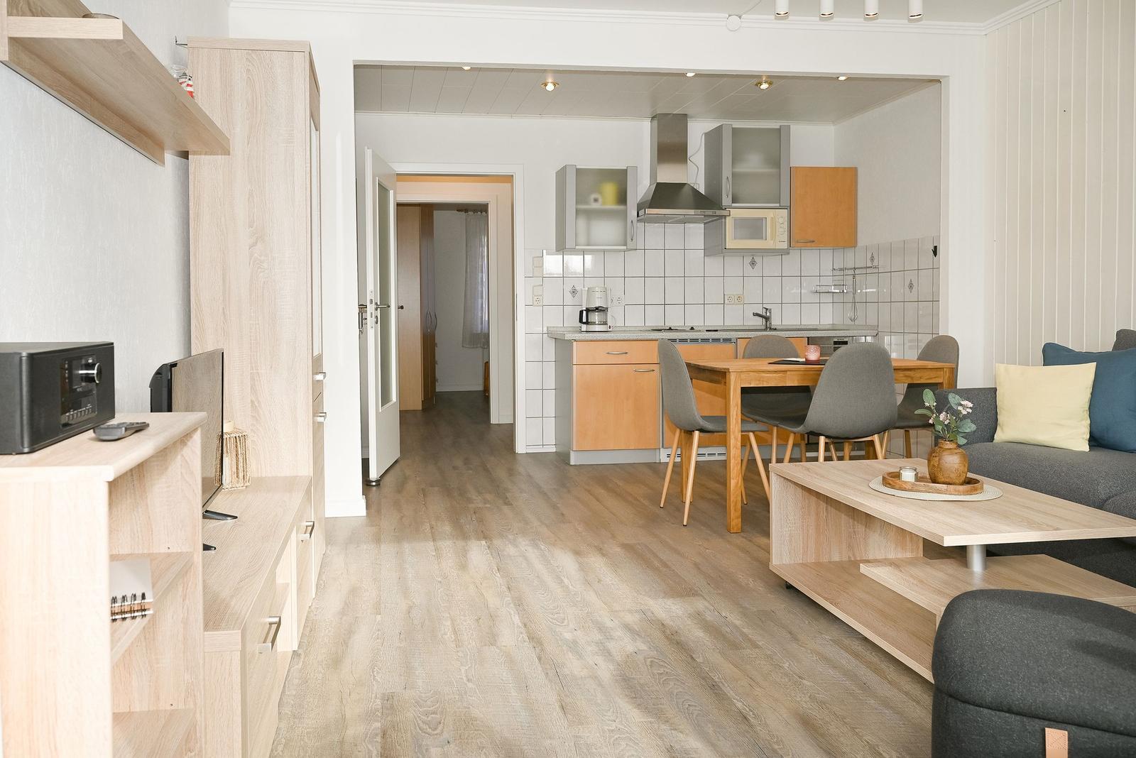 Wohnbereich mit Küche, Esstisch und Sofa. Holzboden und moderne Einrichtung.