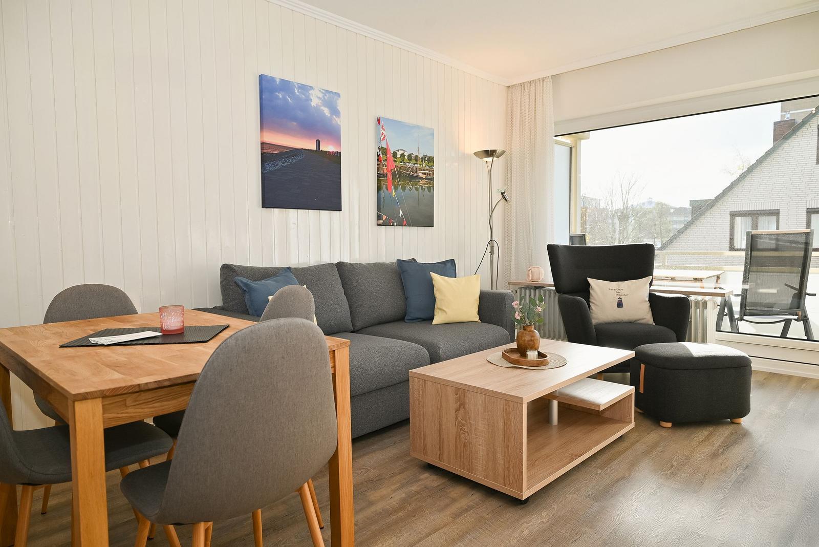 Wohn- und Essbereich mit Sofa, Tisch und Blick auf Balkon.