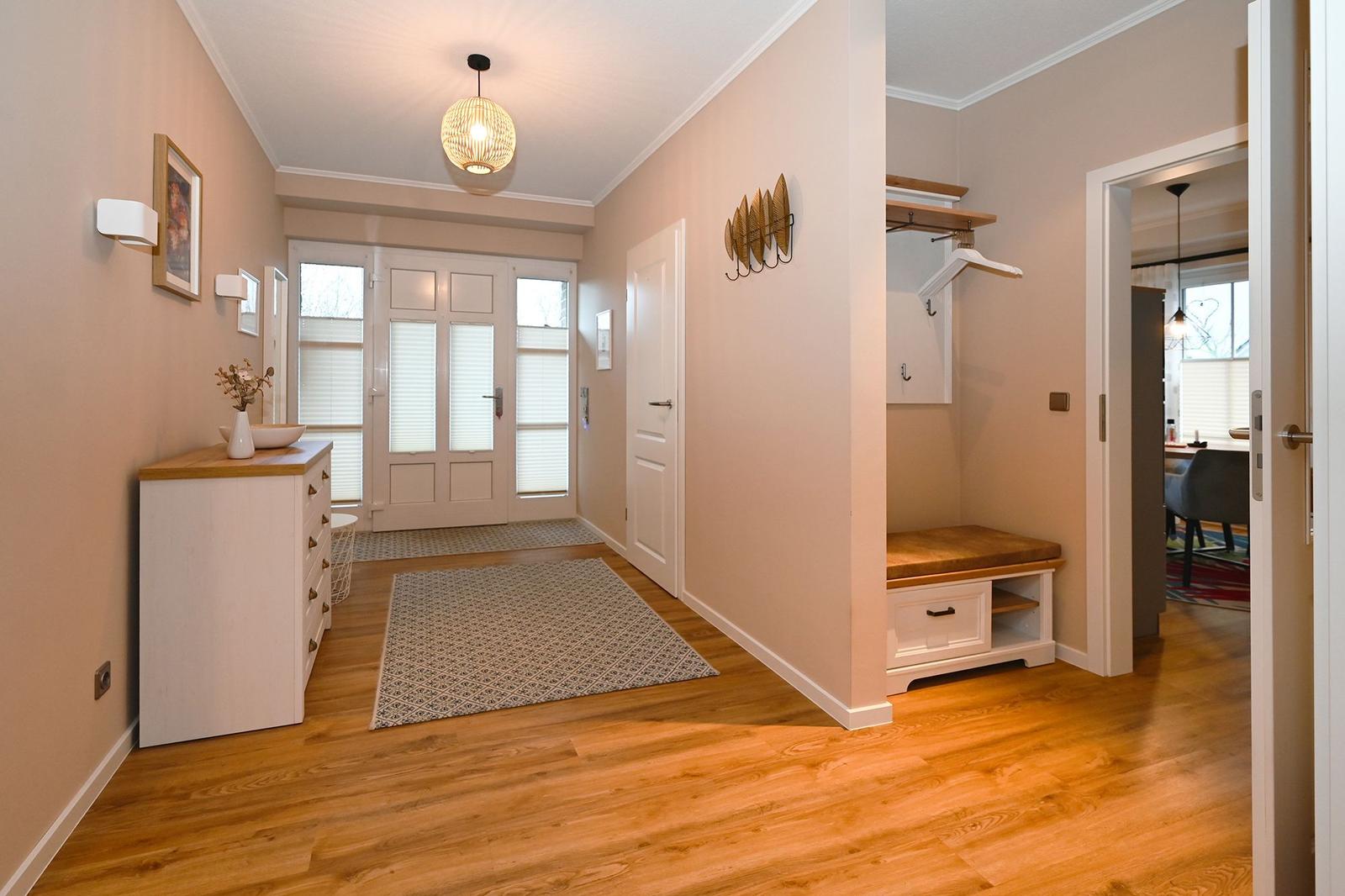 Eingangsbereich mit Holzboden, Schuhschrank und Garderobe. Durchgang zur Küche.