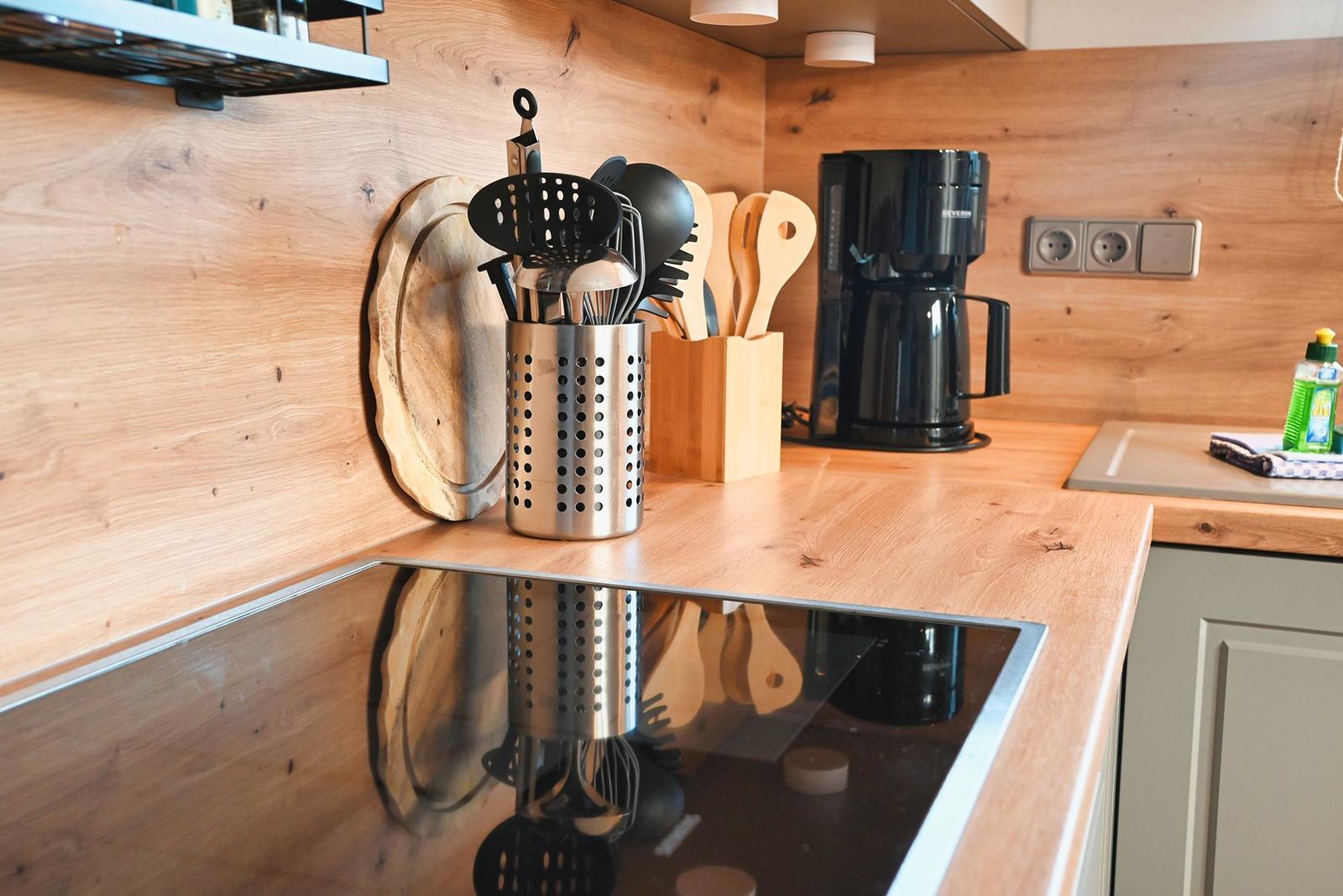 Küche mit Holzoberflächen, Kochutensilien und Kaffeemaschine.