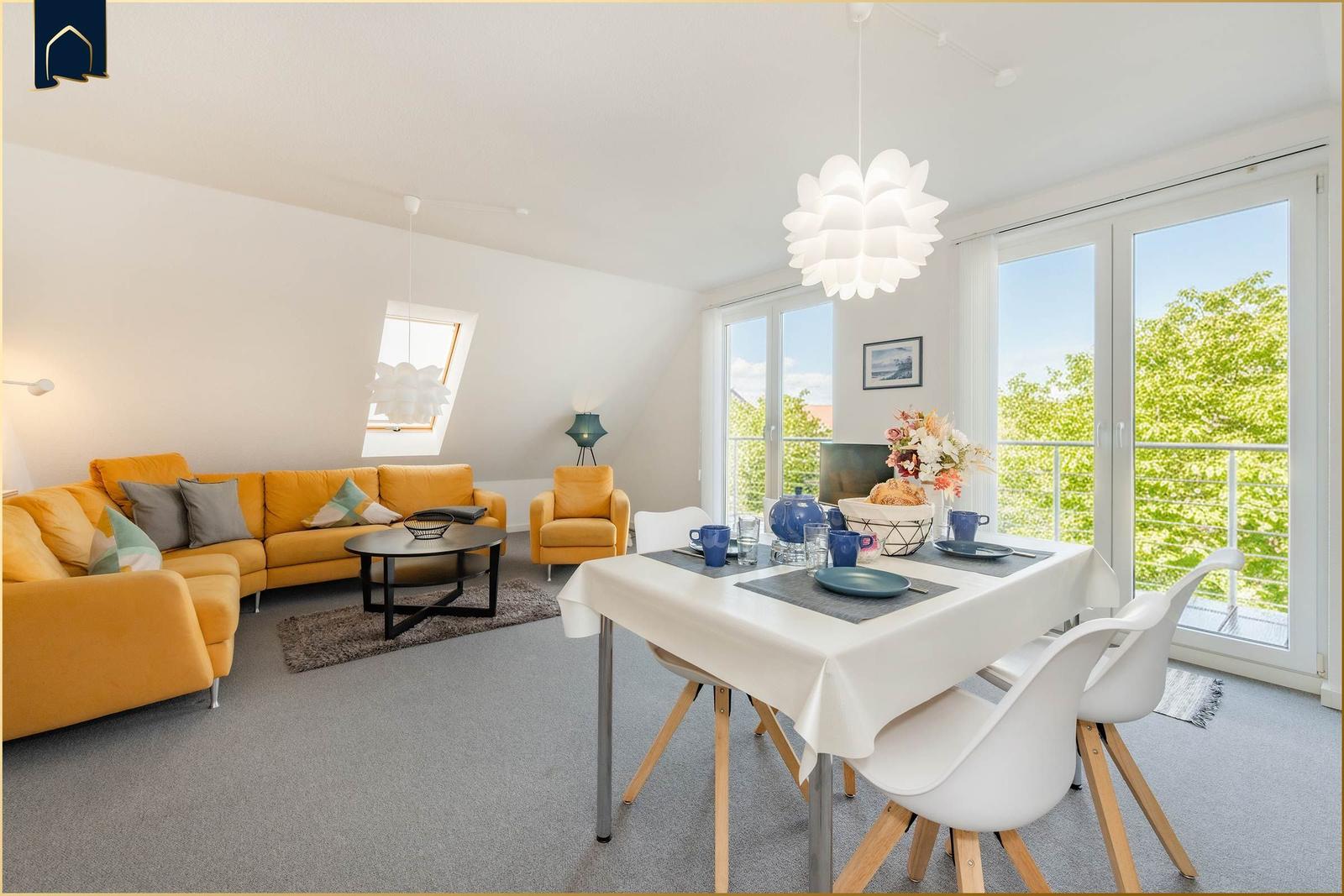 Wohn- und Essbereich mit gelbem Sofa, Esstisch und Balkontür.